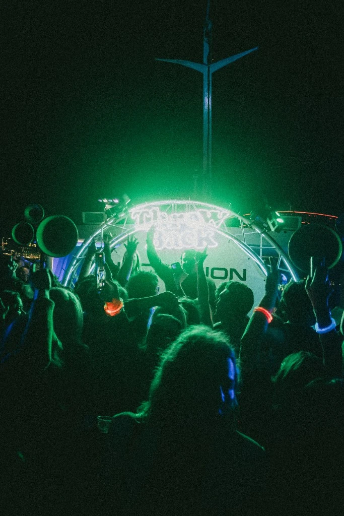 Throw Back neon sign glowing green on the harbour at night